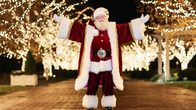 Santa Claus in front of illuminated lights on Watkins Lane