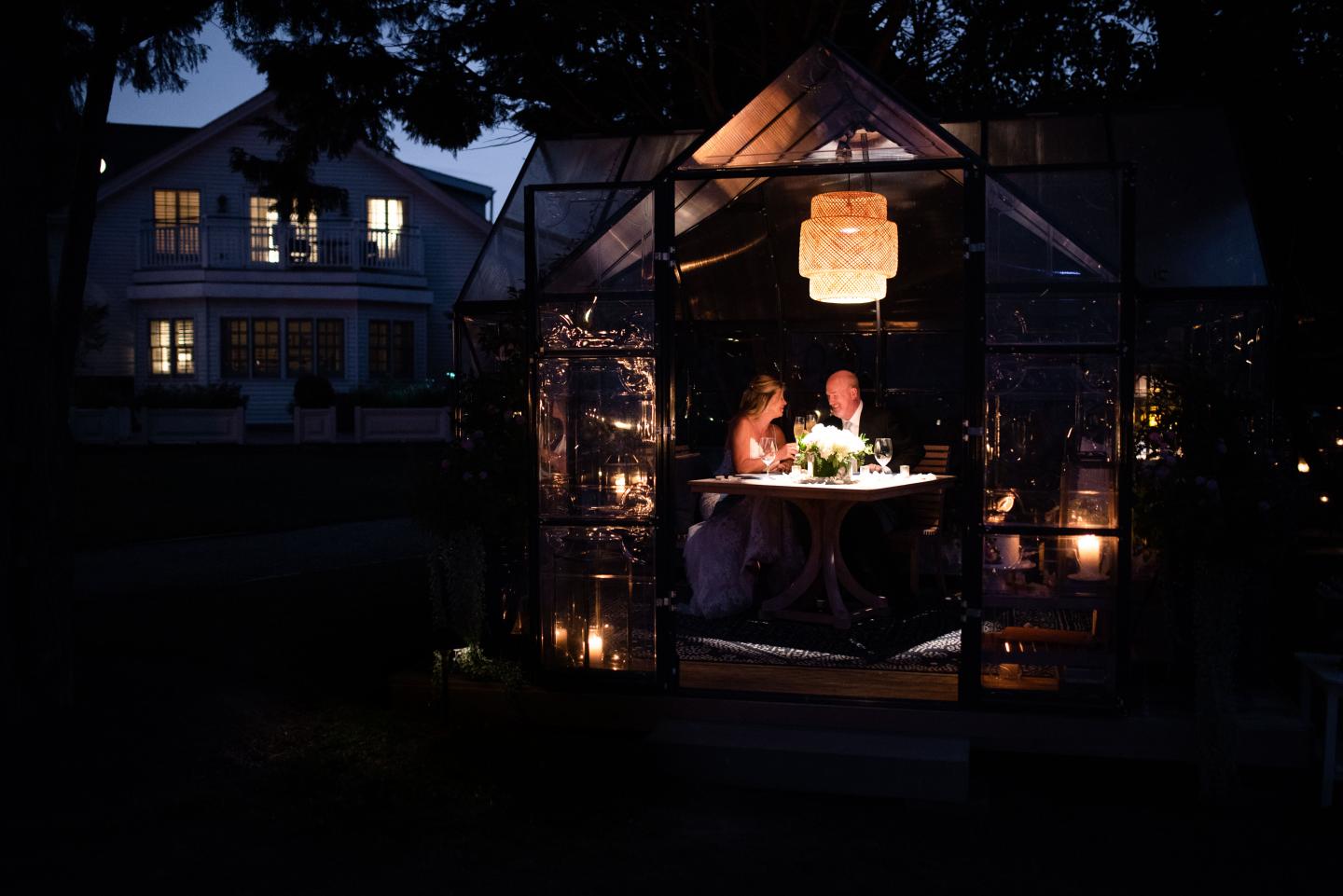Couple dining inside a lit gazebo at night