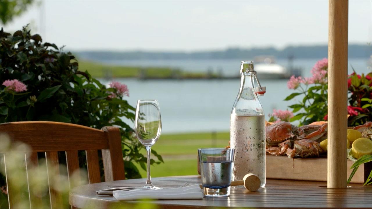 Wine glass and bottle on a patio table overlooking the ocean