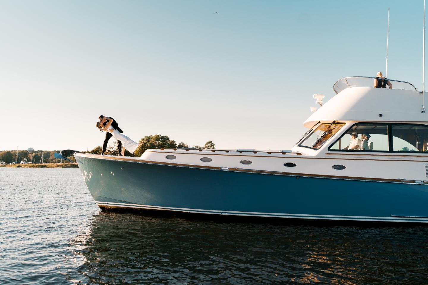 Bride and groom kissing on the bow of Five Star Hinckley Yacht 