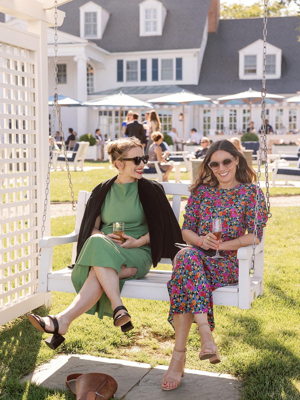 Guests enjoying waterfront glider swing with cocktails.