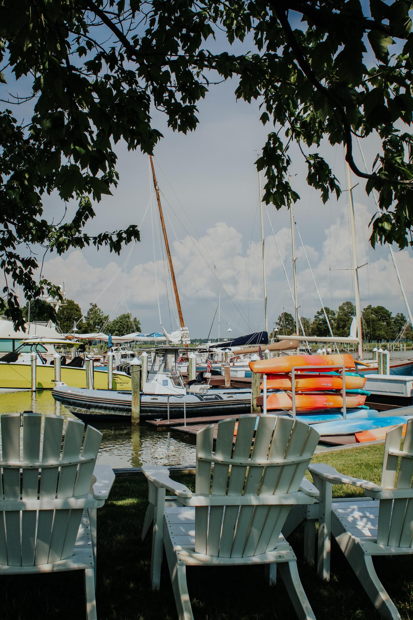 Two shaded Adirondack chairs overlooking the bustling dock
