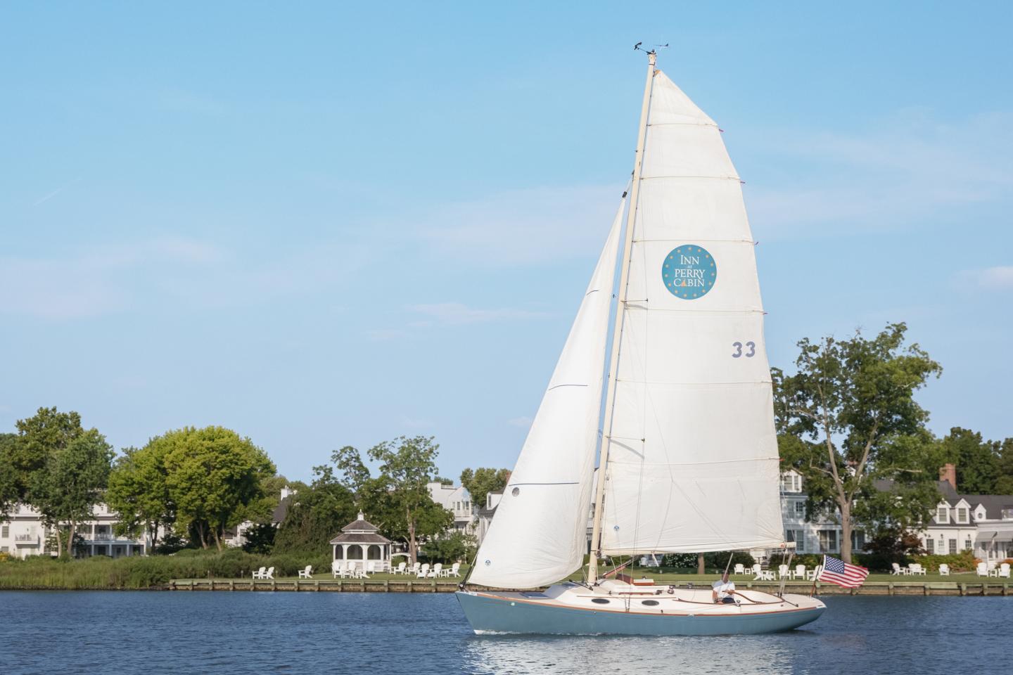 Sailboat full sail on the Miles River in front of the Inn at Perry Cabin