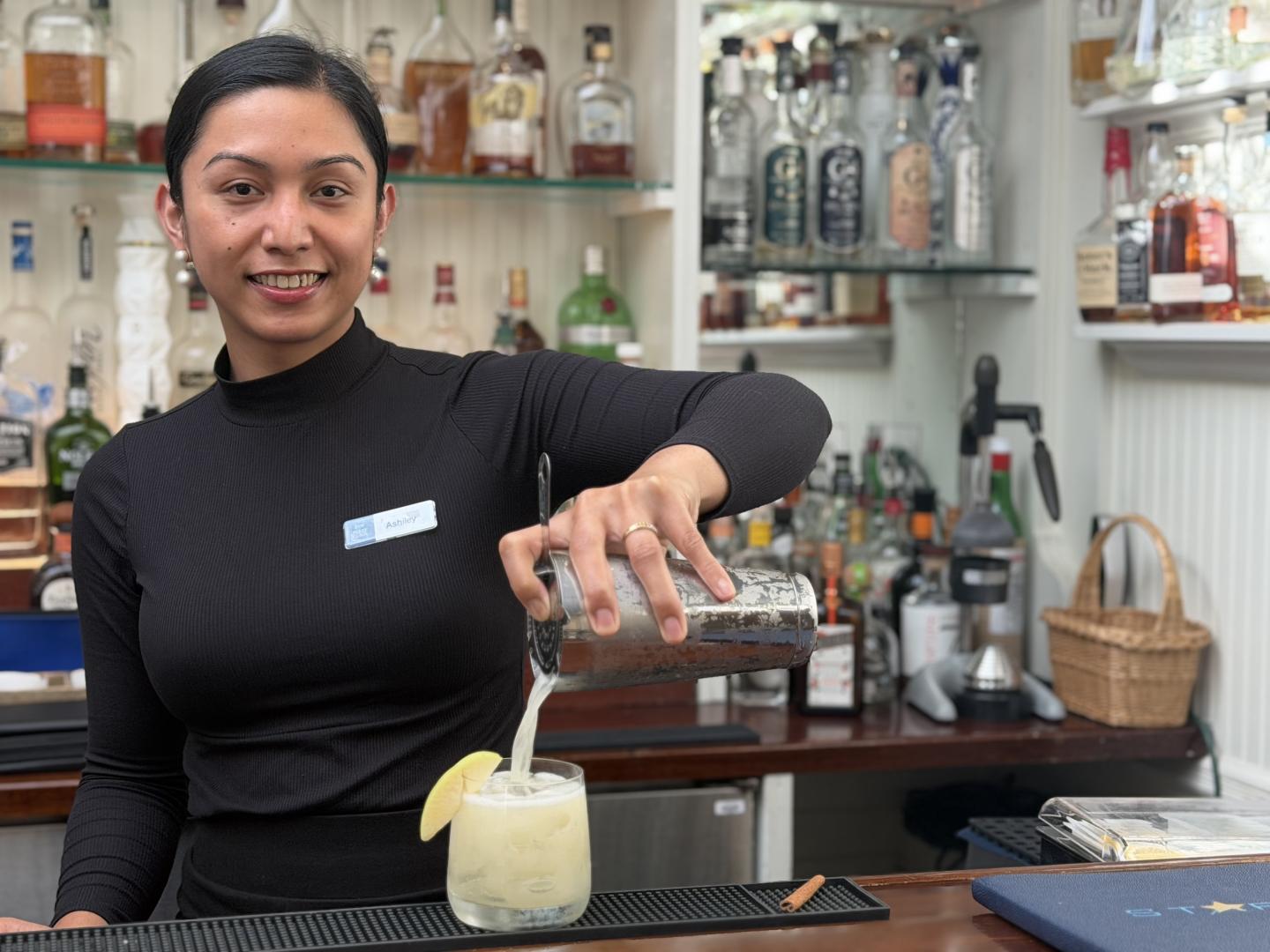 Ashiley in Purser's Pub pouring seasonal cocktail Autumn on the Miles