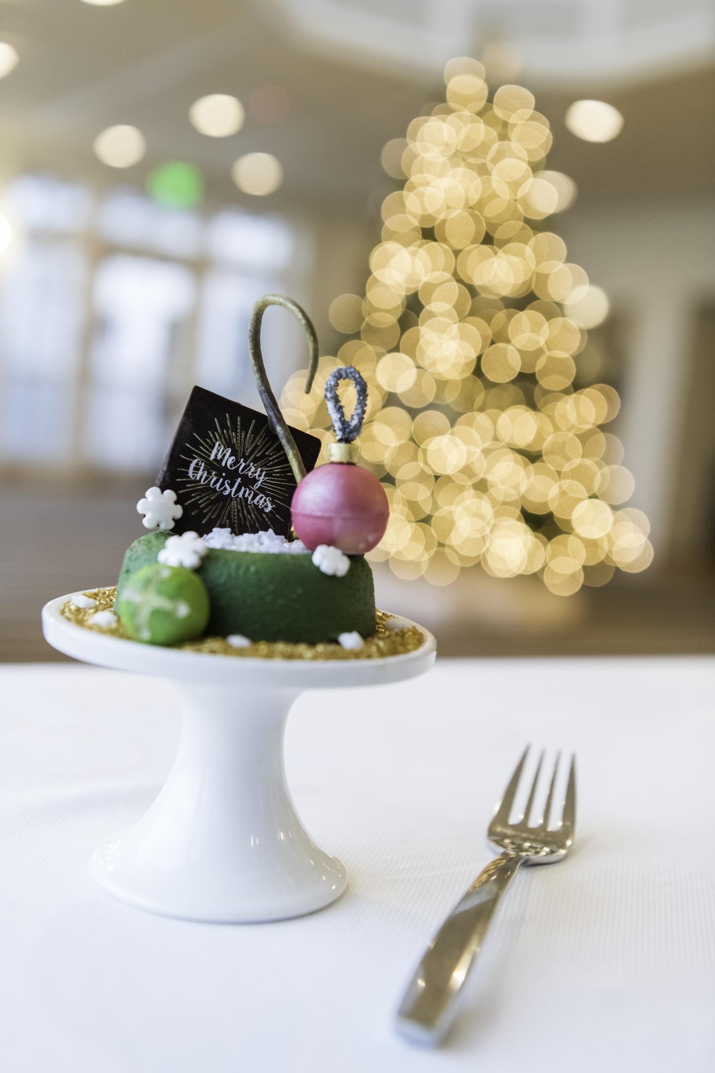 Chocolate "Merry Christmas" Dessert in front of decorated Christmas Tree